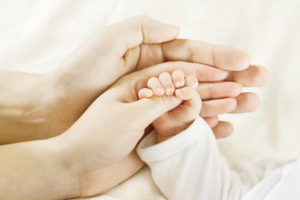 Birth Injury Lawyer Bloomington, IL- father and mother holding babies hand