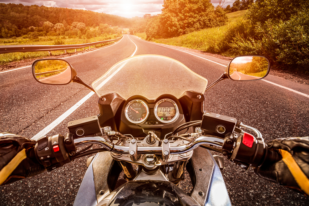 5 Things to Know Before Filing a Motorcycle Accident Lawsuit - Biker driving a motorcycle rides along the asphalt road. First-person view.