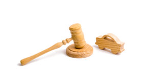 Civil Asset Forfeiture Lawyer Bloomington, IL - Wooden figurine of a car with a hammer of the judge on a white background. Minimalism. Purchase and sale of the car. The trial, confiscation of the machine. Recognition of ownership.